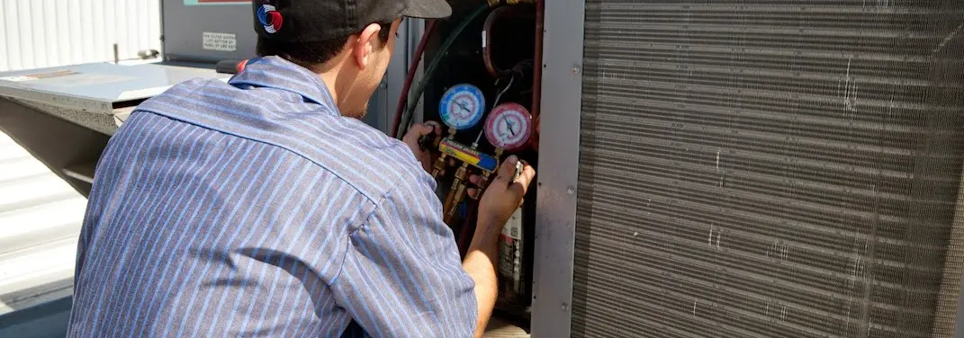 HVAC technician servicing a condenser unit in Magalia